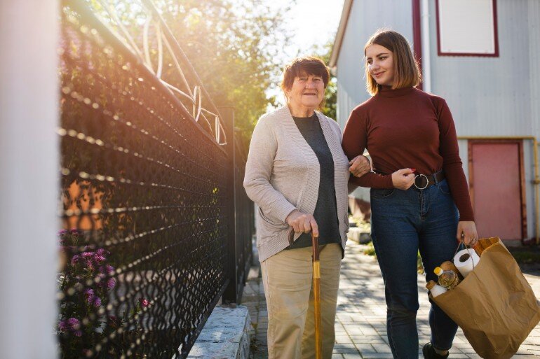 Woman helping an elderly neighbour with groceries