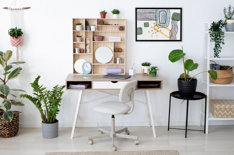 A modern designed wooden desk, with pine shelves behind and plants to either side