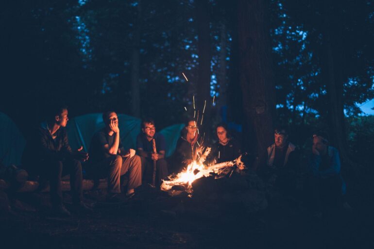 Group of people at a campsite sitting around a fire
