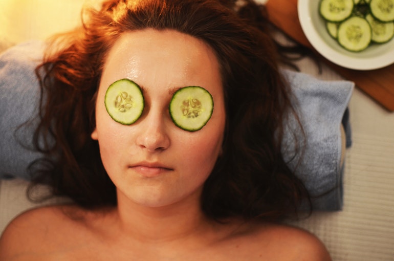 Woman wearing a facemask and cucumbers