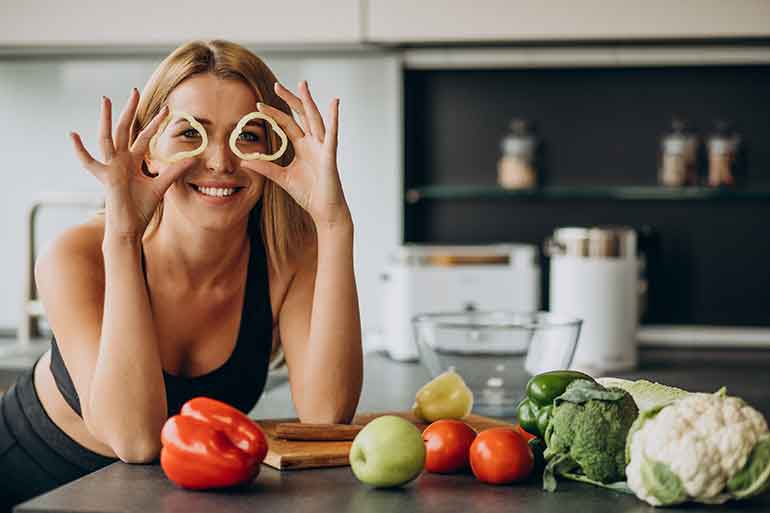 Smiling woman using cut peppers as glasses