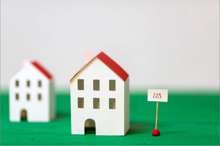 Miniature model house near a for sale sign