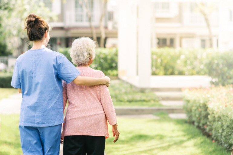 Carer and elderly resident in a care home garden