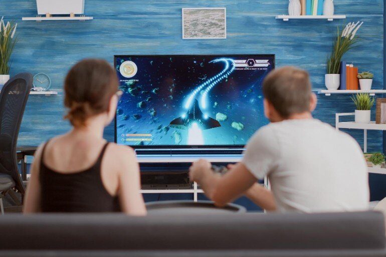 Couple sitting on a sofa playing a computer game on their television