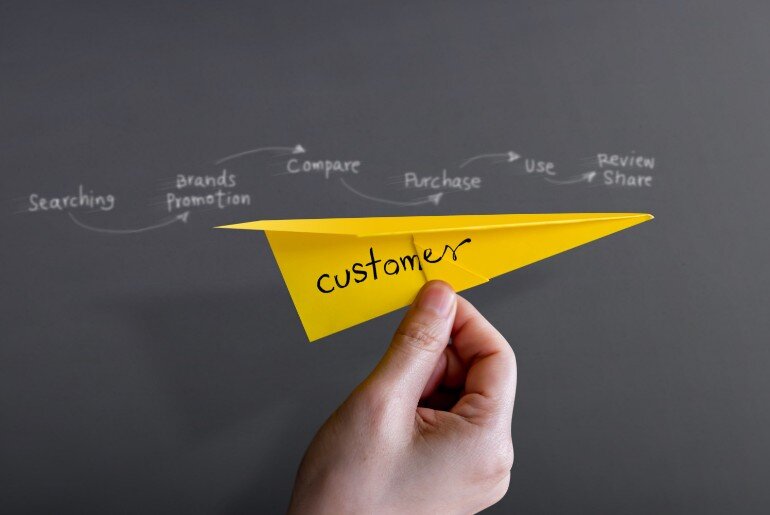 Customer experience journey concept image showing a paper airplane held against a blackboard