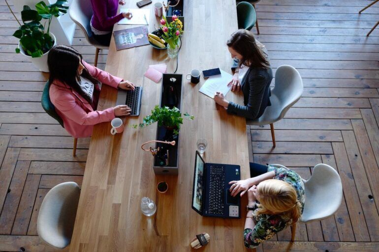 Group of people working at a large wooden table