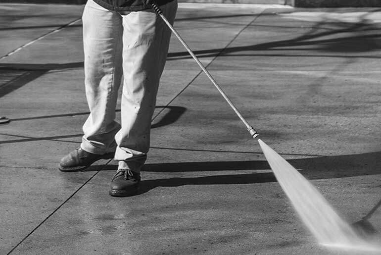 Black and White photo of a person jet washing paving