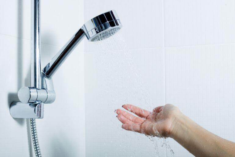 Person holding their hand in a shower to test the temperature of the water