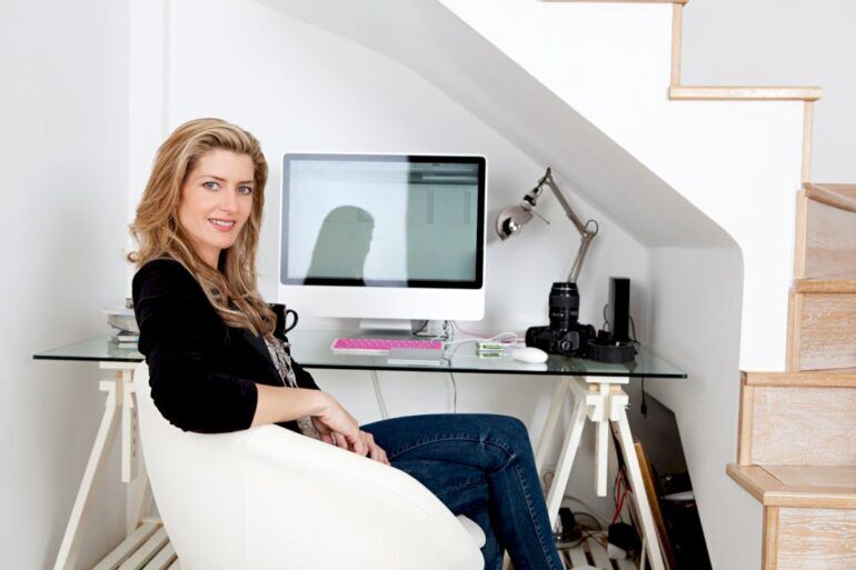 Woman sitting at a home office desk situated under the stairs