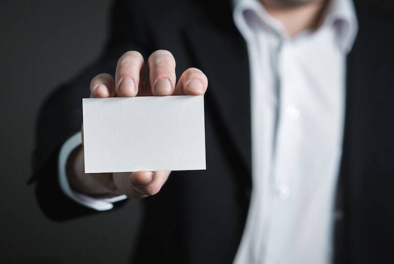 Person holding a blank business card out towards the camera