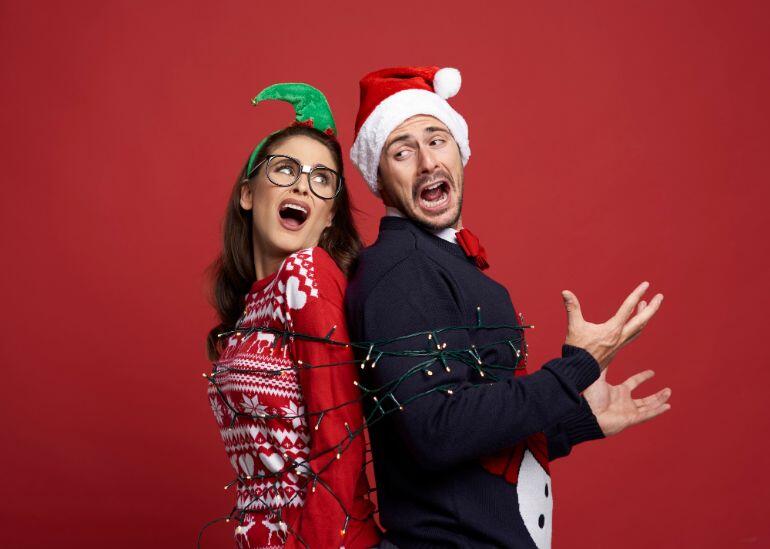 Couple dressed in festive clothes tied up in fairy lights