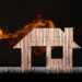 Wooden cutout in the shape of a house with flames coming from the roof