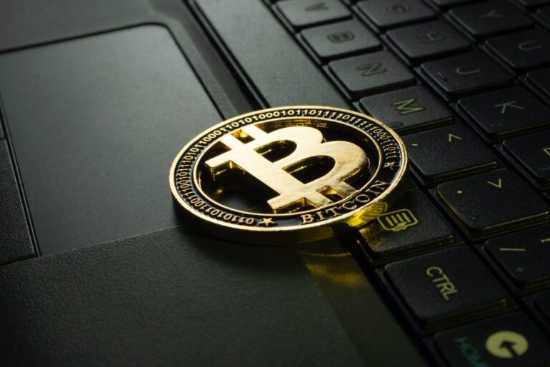 Image of a gold coin featuring the Bitcoin logo placed on a laptop keyboard