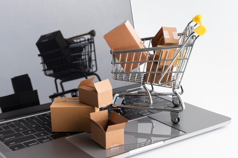 Model of a shopping cart filled with packages sitting on a laptop keyboard