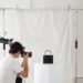 Person in a photography studio taking a photo of a handbag