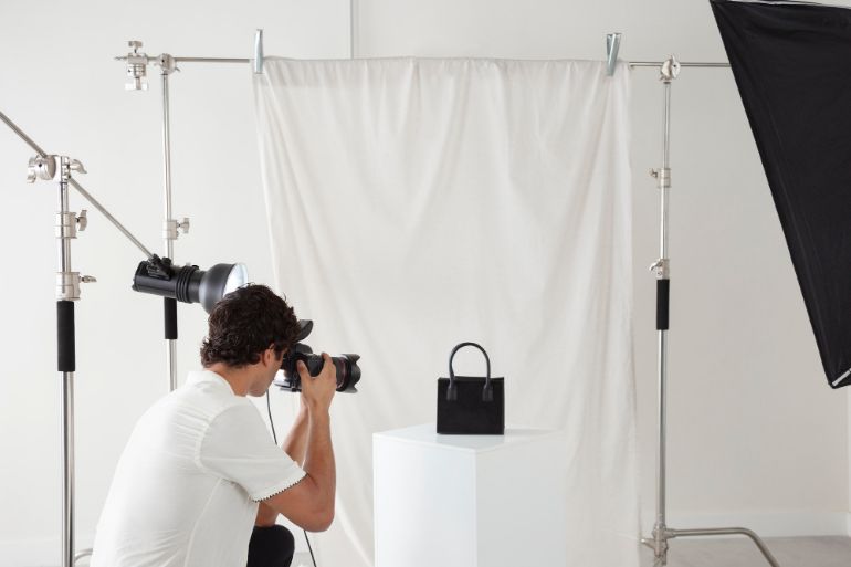 Person in a photography studio taking a photo of a handbag