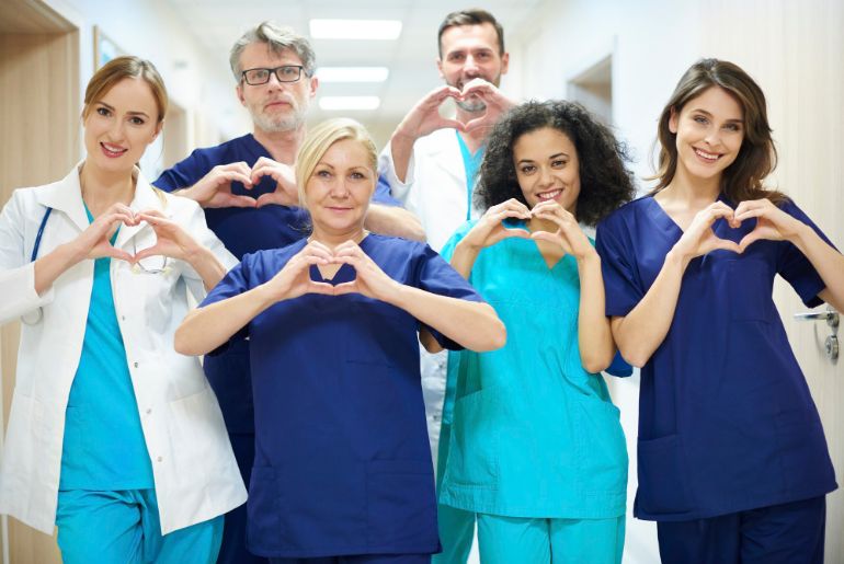 Group of medical professionals making heart shapes with their fingers