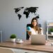 Smiling woman sat at an office desk holding a globe