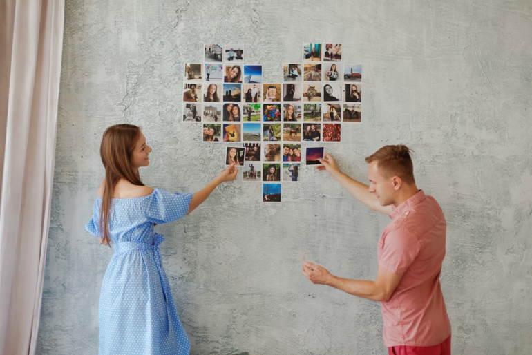 A couple placing photos on a wall in the shape of a heart