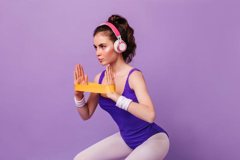 Woman wearing workout gear and headphones using resistance bands