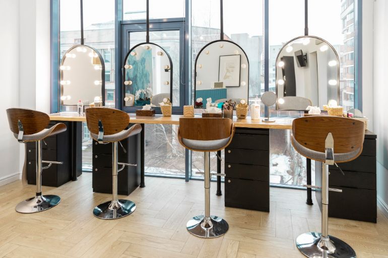 Photo of a modern beauty salon with high stools and mirrors with bulbs around them