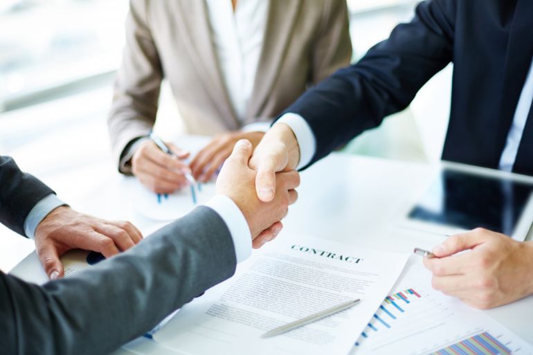 Person shaking hands over a contract