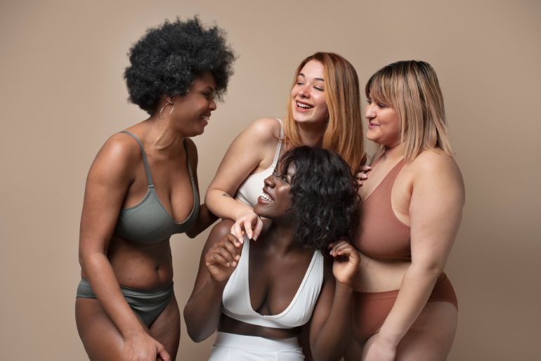 A group of smiling women wearing different shades of underwear