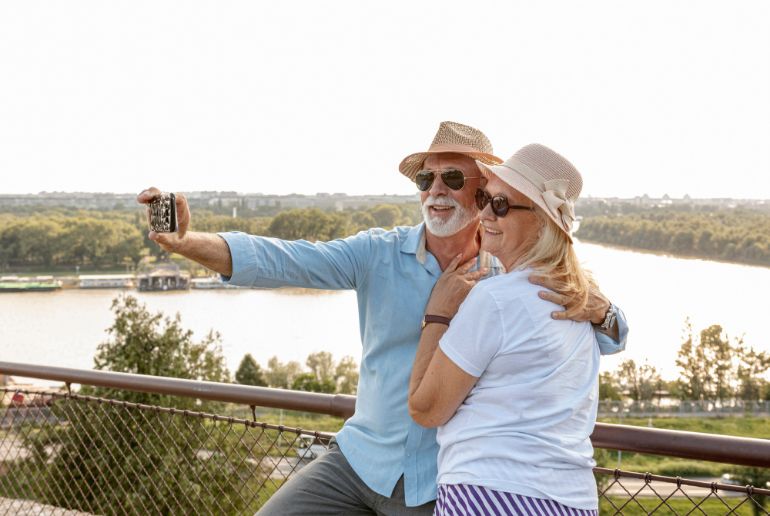 A retired couple taking a selfie by the edge of a cliff