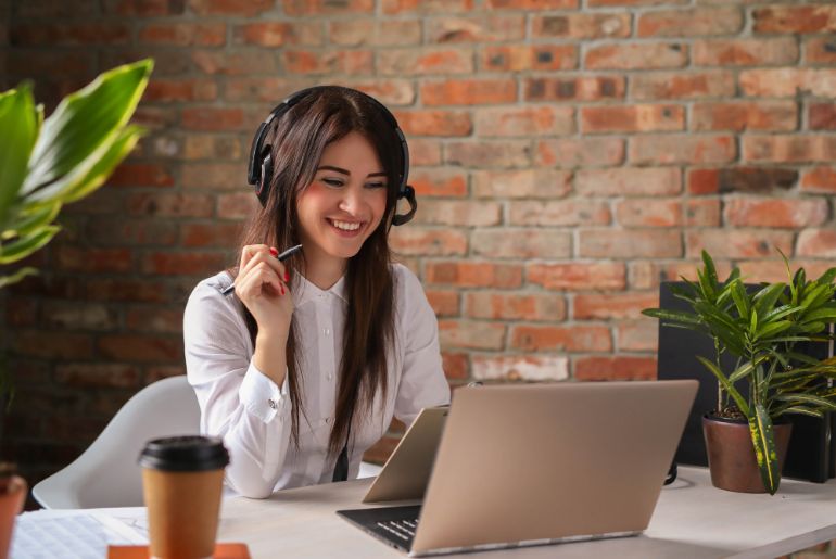 Smiling woman wearing a headset looking at a laptop