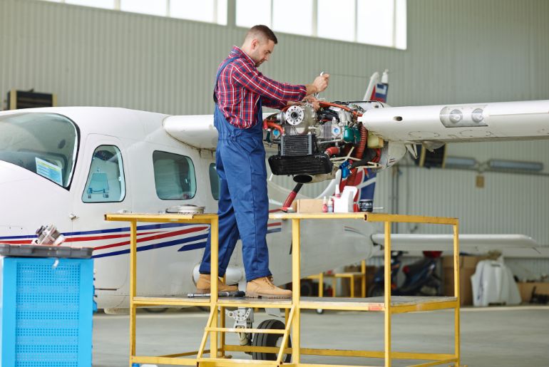 An aircraft mechanic working on the engine of a light aircraft