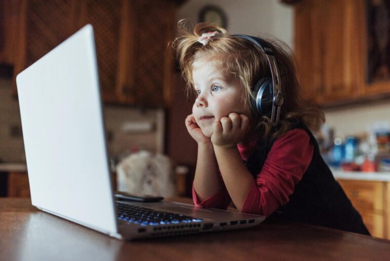 Young child wearing headphones and looking at a laptop
