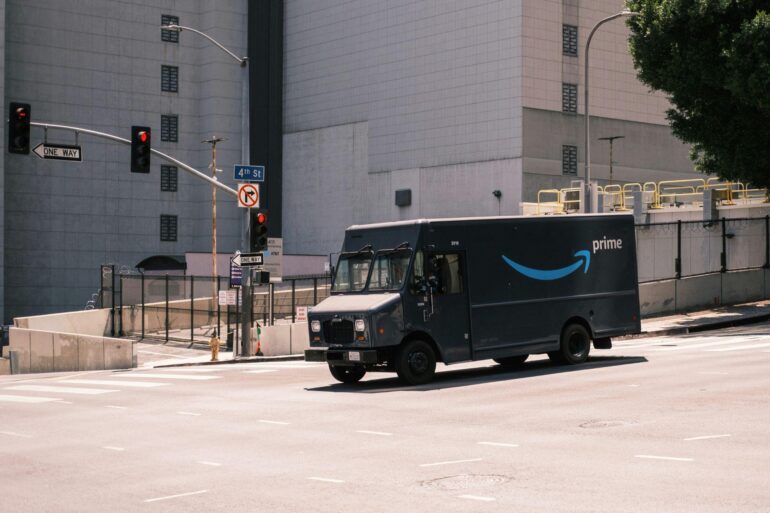 An Amazon delivery truck going through a set of traffic lights