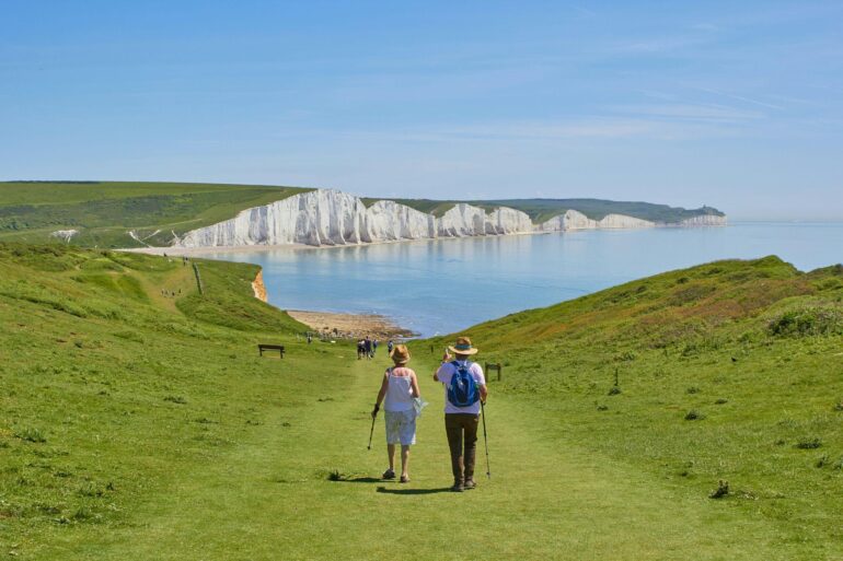 Two people walking along a clifftop towards the sea