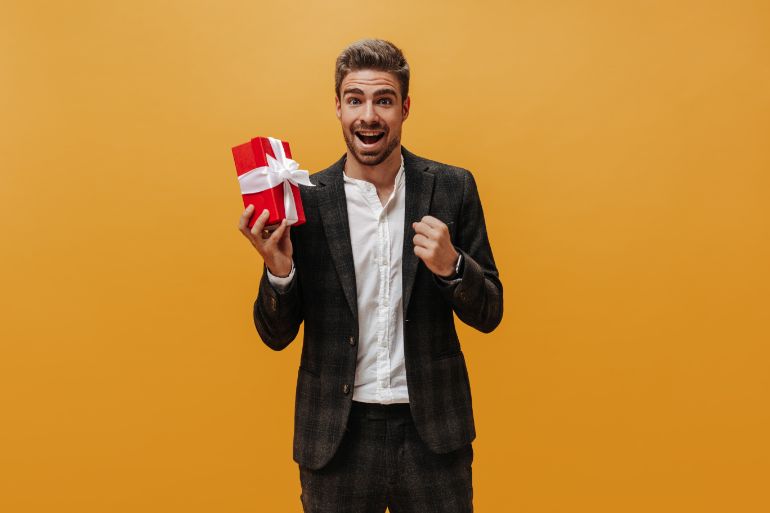 Smart dressed man holding a wrapped gift