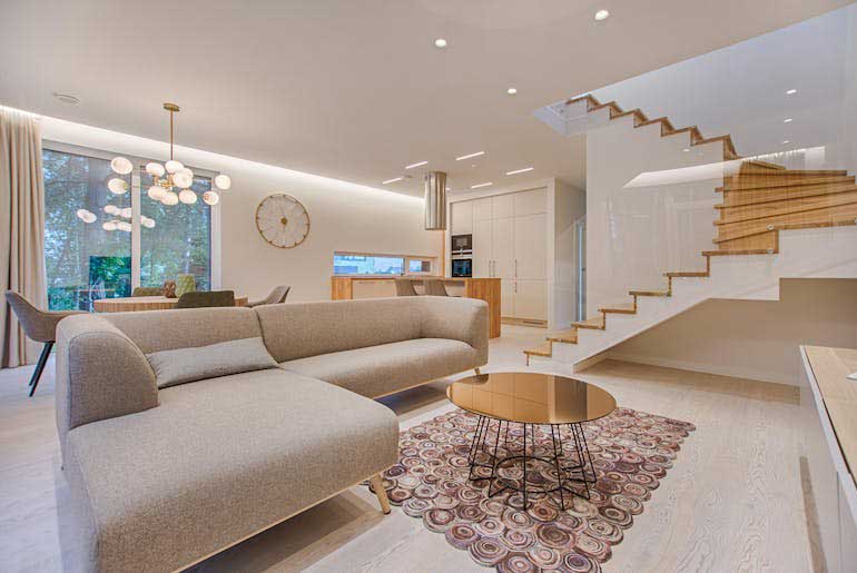 A bright, light room with a pine staircase and a statement rug