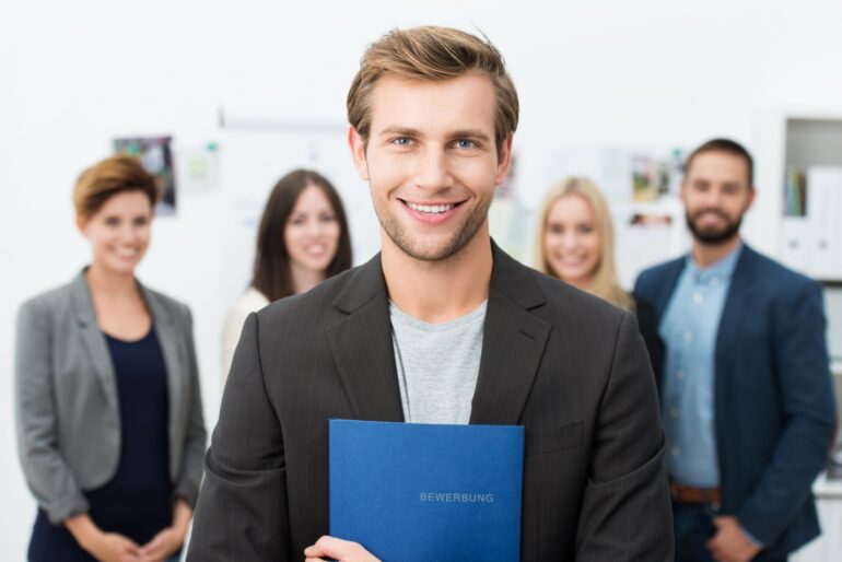 A person holding a blue folder with people behind him