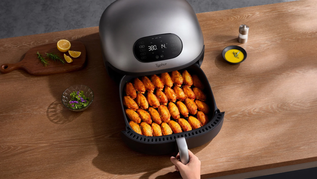 A person opening an air fryer drawer filled with food