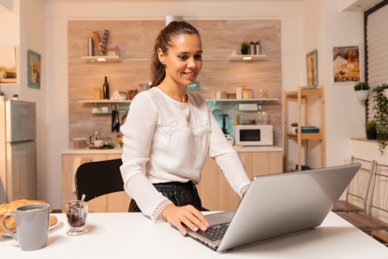 A woman working on a laptop set on a kitchen counter